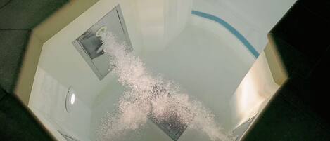 A bathtub with a showerhead and a visible drain.