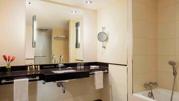 A modern bathroom with a double sink, a large mirror, a handheld showerhead, and a towel rack.