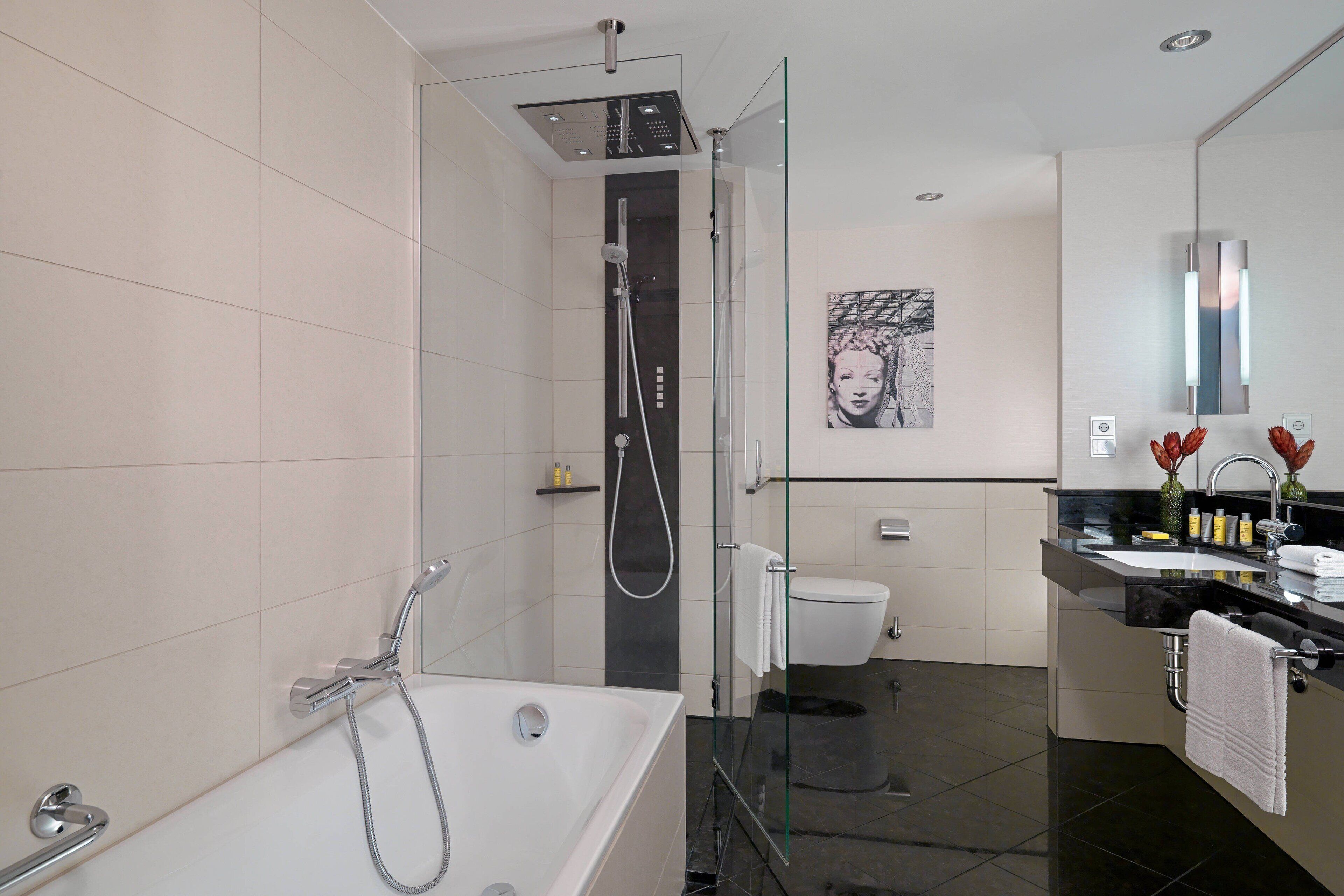 Een moderne badkamer met een douchecabine van glas, een vrijstaand bad, een toilet en een wastafel met spiegel.