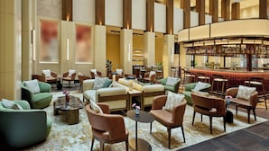 A spacious lobby with multiple seating areas, a central bar, and a high ceiling with wooden accents. - Berlin Marriott Hotel (Berlin)