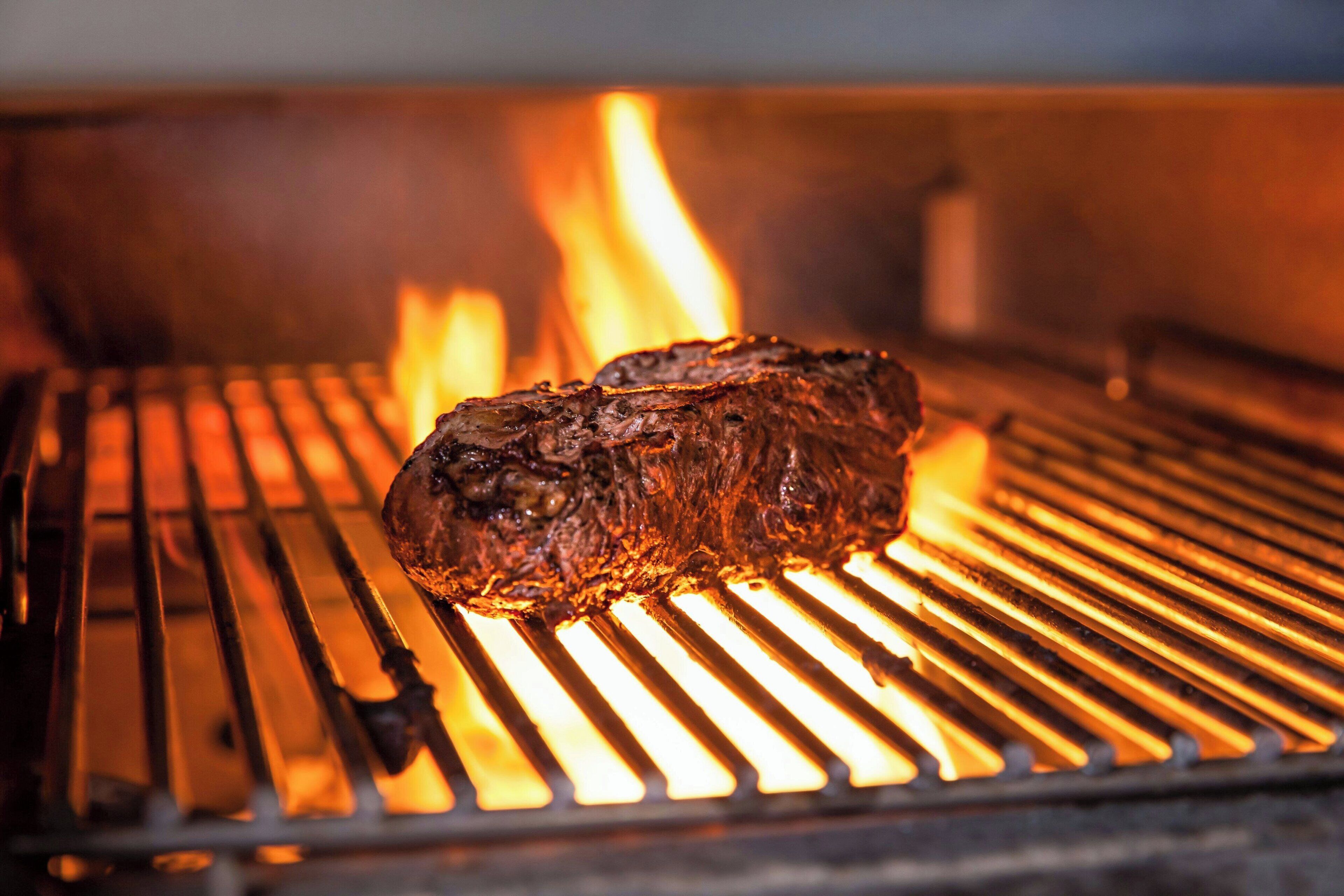A steak grilling over an open flame.