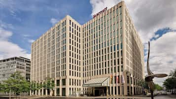 Un hotel alto y moderno con un llamativo letrero de 'Marriott', ventanas amplias y un patio central con una fuente.