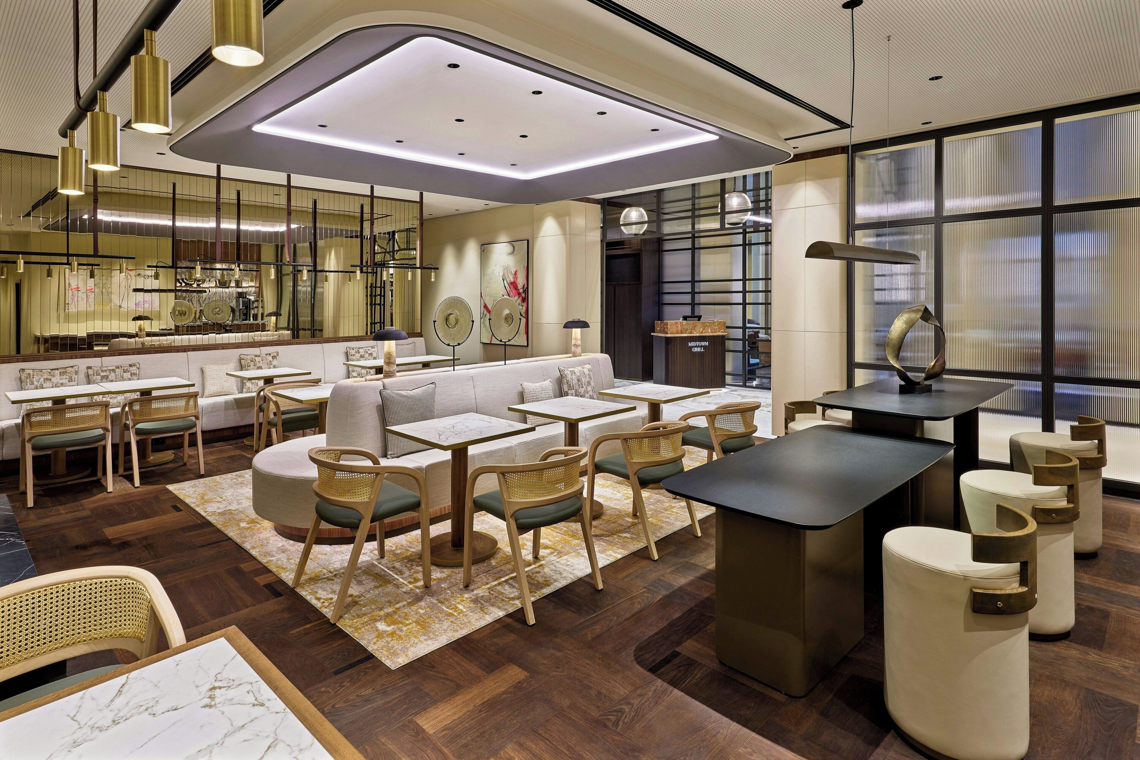 A modern hotel lobby with a bar area, seating arrangements, and a large window providing a view.