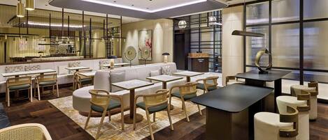A modern hotel lobby with a bar area, seating arrangements, and a large window providing a view.