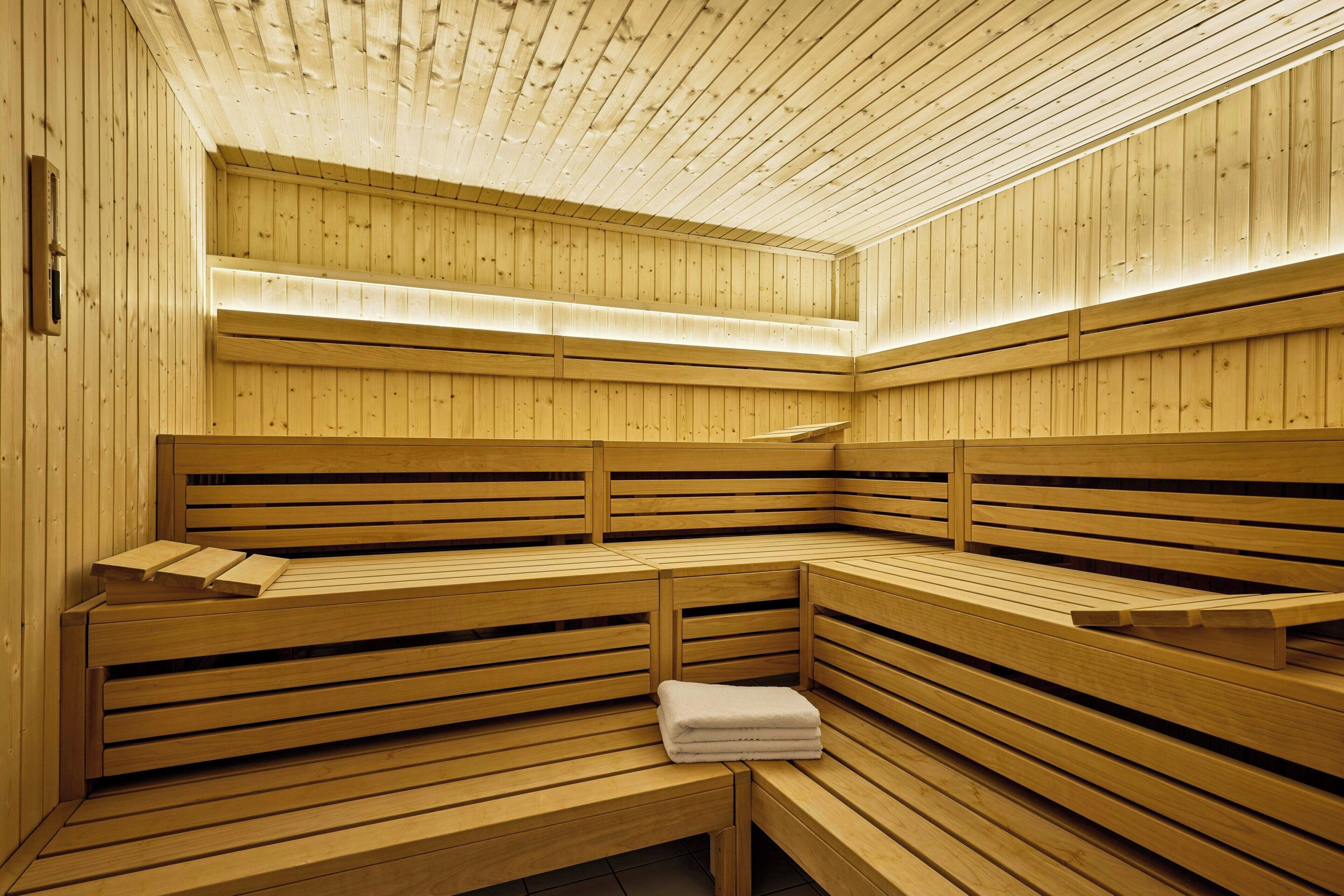 Una sauna con bancos de madera, una toalla sobre uno de ellos y techo de madera.