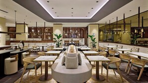 A modern restaurant with round tables, cushioned seating, and a central bar area. - Berlin Marriott Hotel (Berlin)