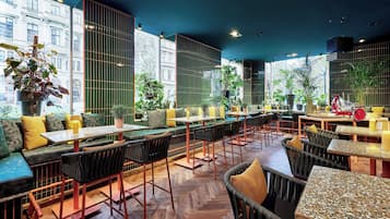 Un restaurante moderno con techos altos, amplias ventanas y diversas opciones de asientos, incluyendo cabinas y mesas.