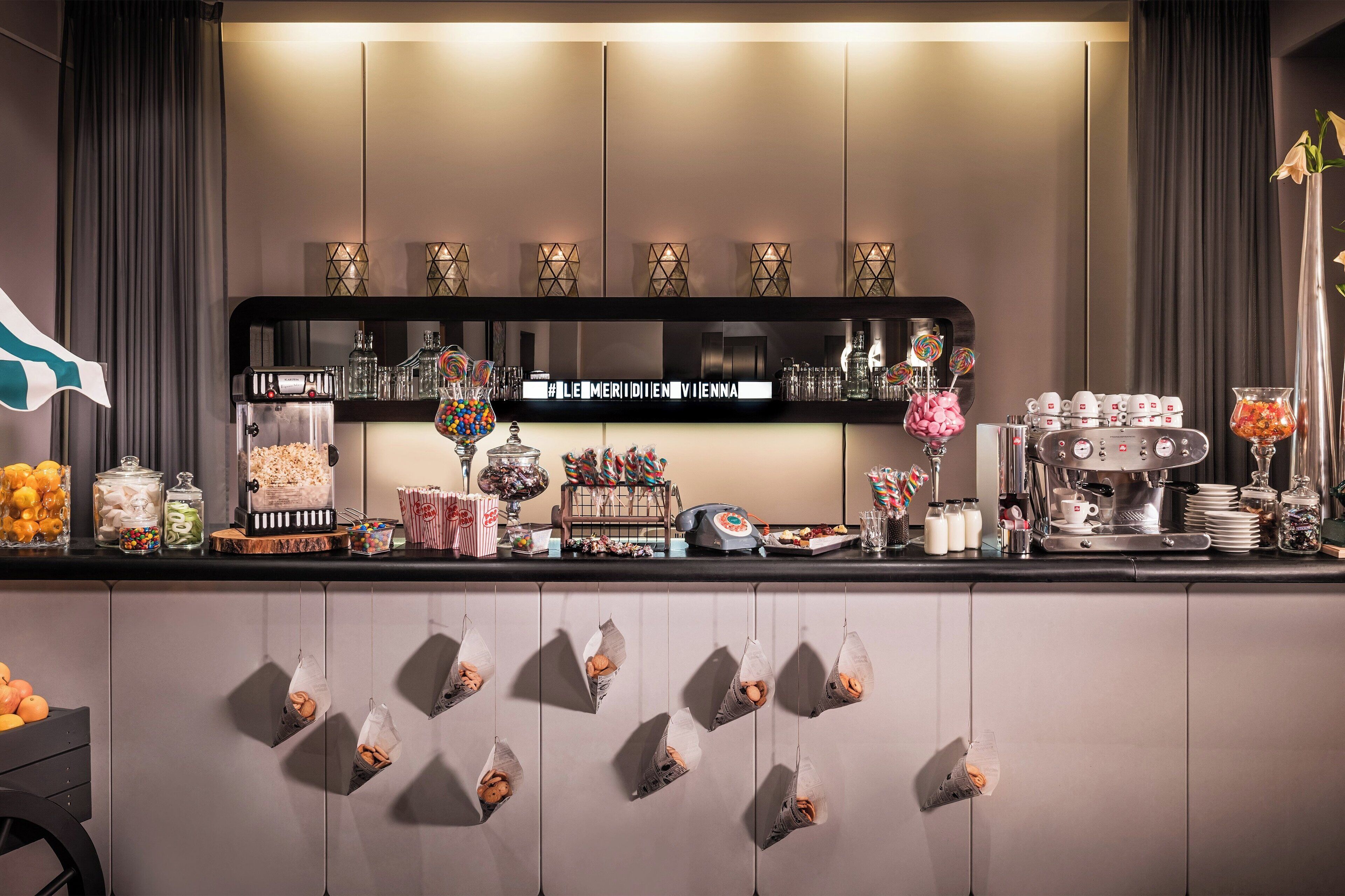 A bar area with shelves of bottles, glasses, and snacks.