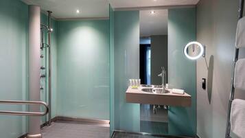 Un baño moderno con cabina de ducha de vidrio, tocador con espejo y un perchero para toallas.