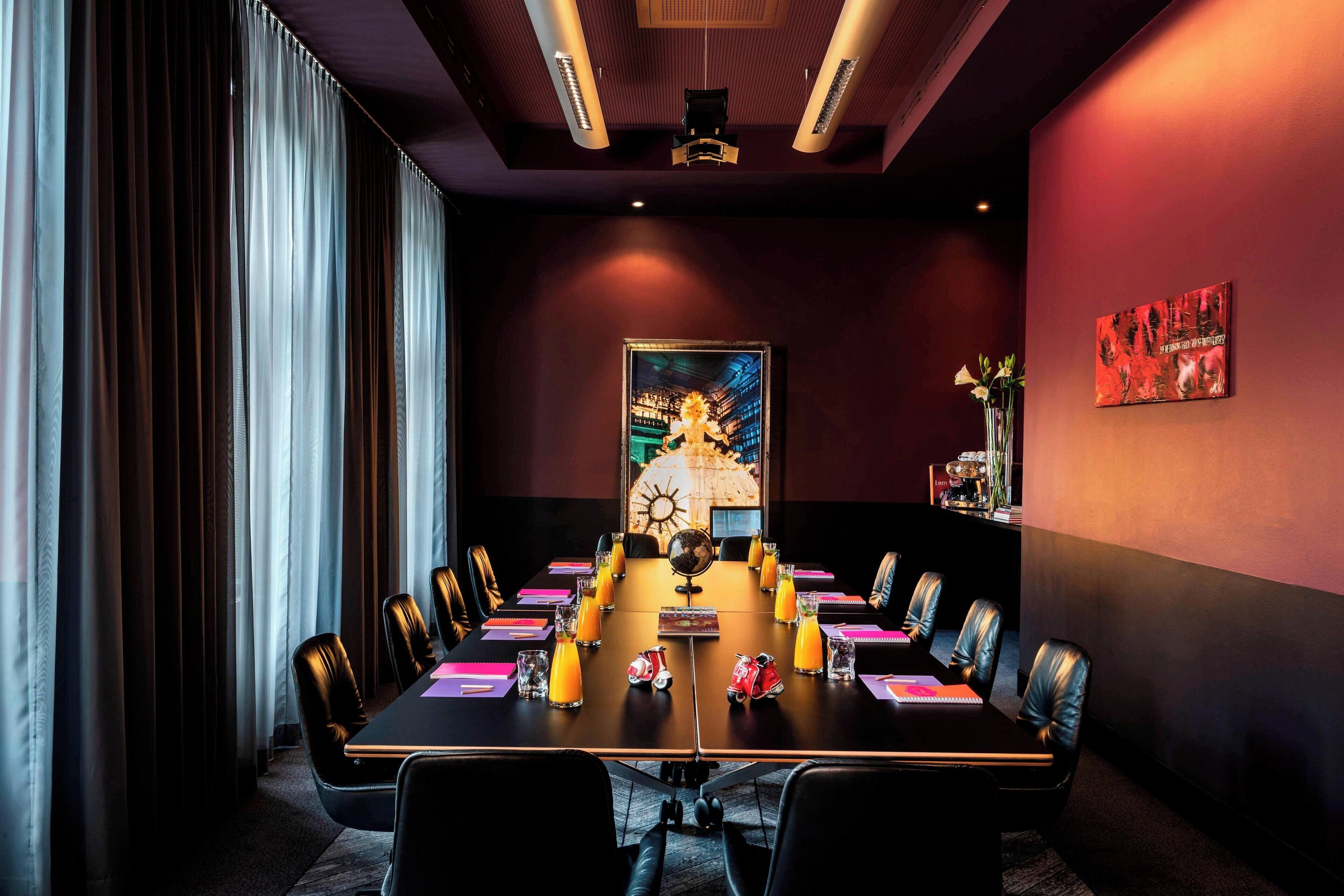A conference room with a long table, chairs, a globe, and a painting on the wall.