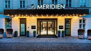 Das Äußere des Hotels Le Meridien mit einer klassischen Fassade, Eingangstüren und Pflanzgefäßen.