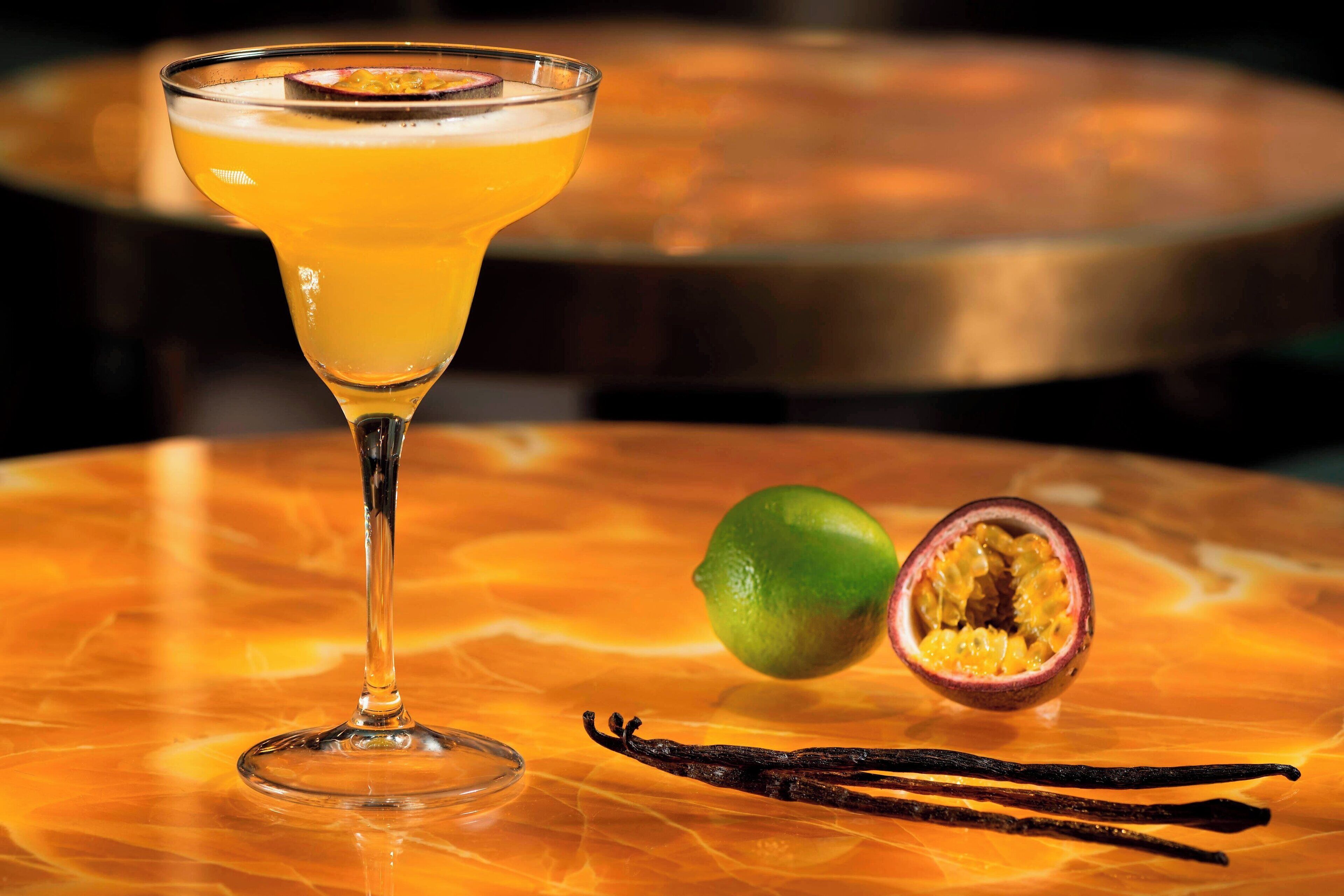 Um copo de cocktail com limão e maracujá sobre uma mesa de mármore.