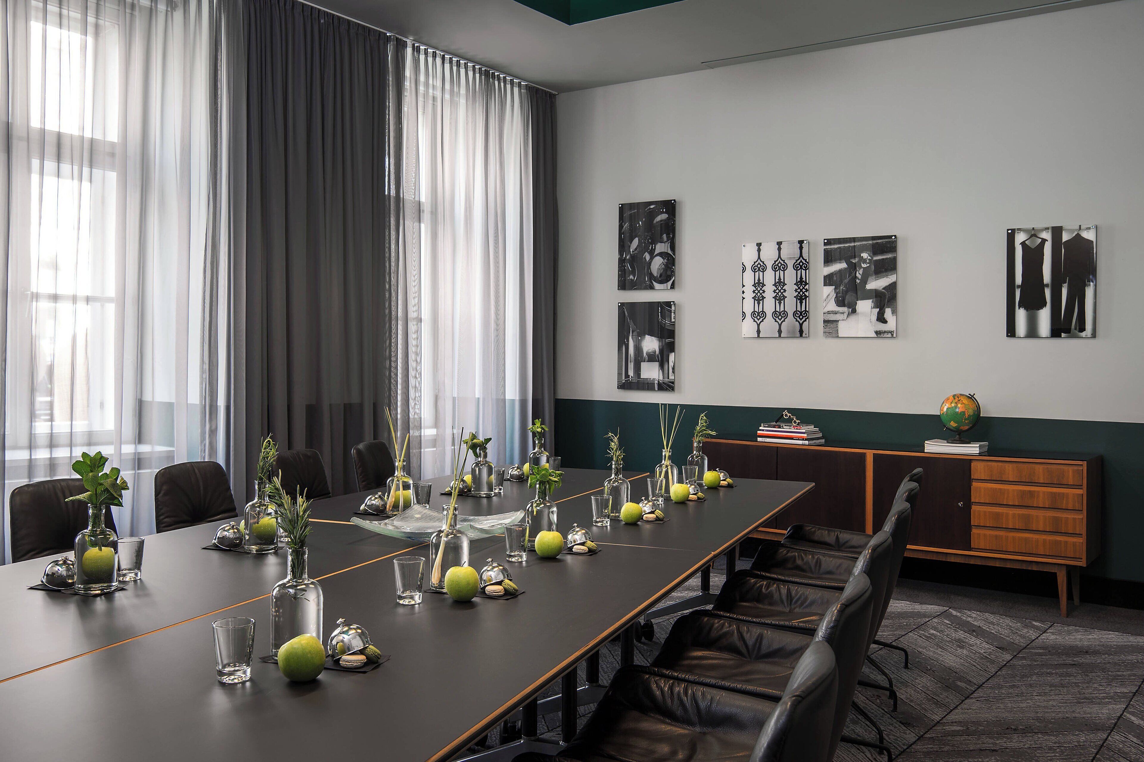 A conference room with a long table, chairs, and a globe on a cabinet.