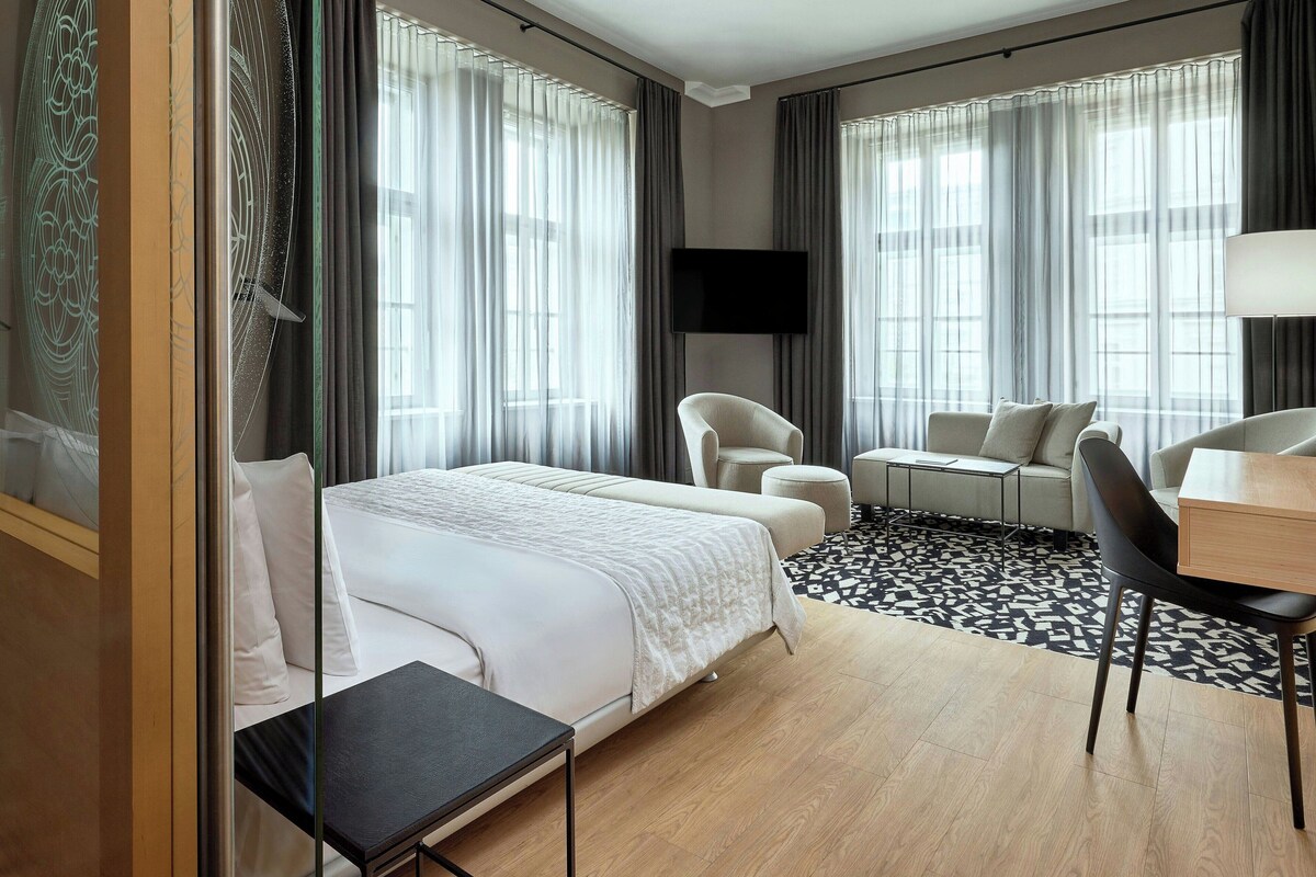 Habitació d'hotel amb llit, escriptori, cadira, sofà i televisió.
