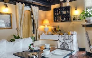 Un área de comedor con una mesa dispuesta para dos personas, una lámpara y una estantería para vinos al fondo.