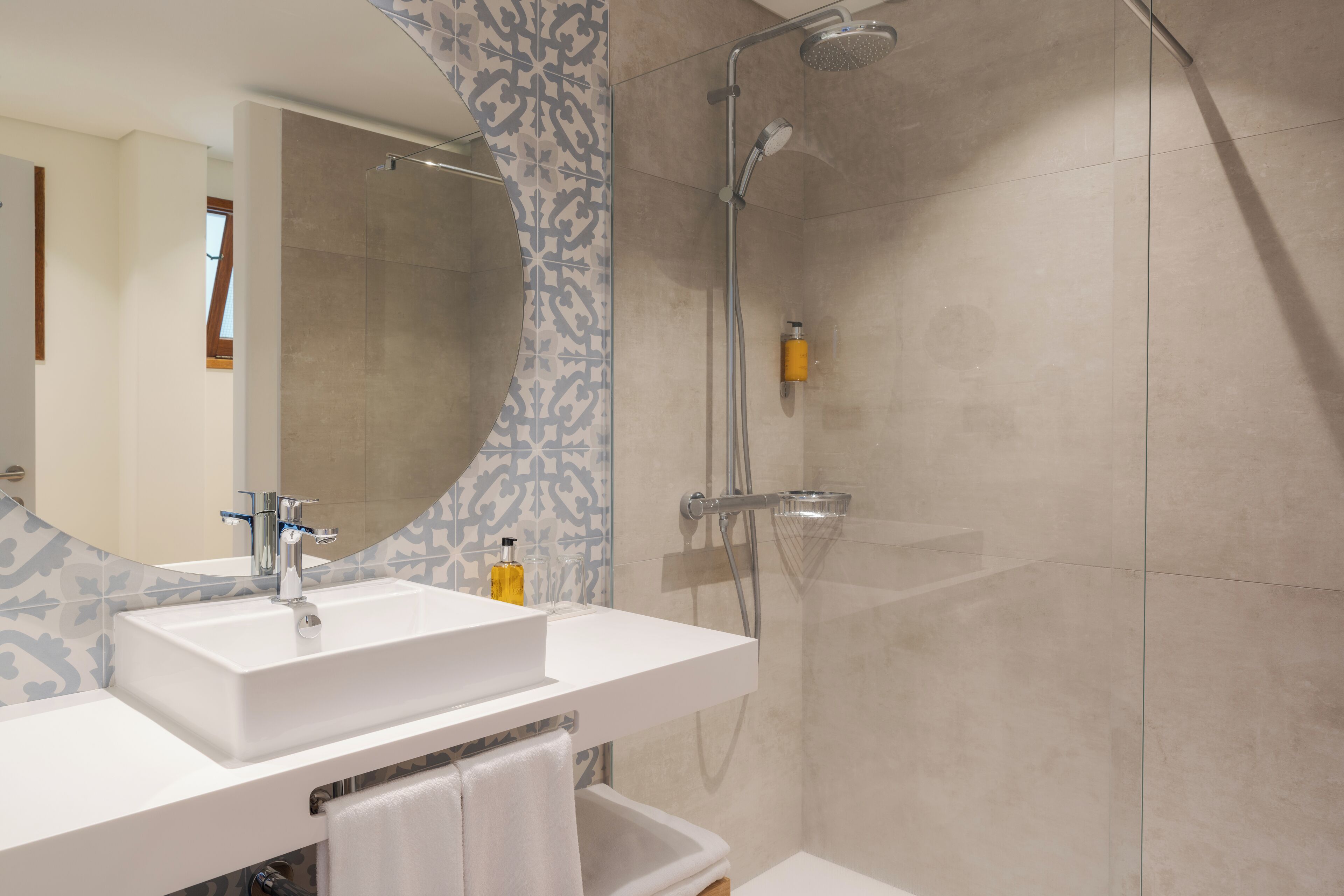 A modern bathroom with a large mirror, a white sink, and a shower area.