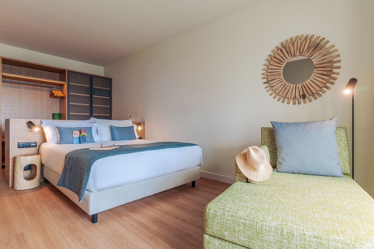 A modern bedroom with a bed, bedside tables, a wall-mounted mirror, and a floor lamp.