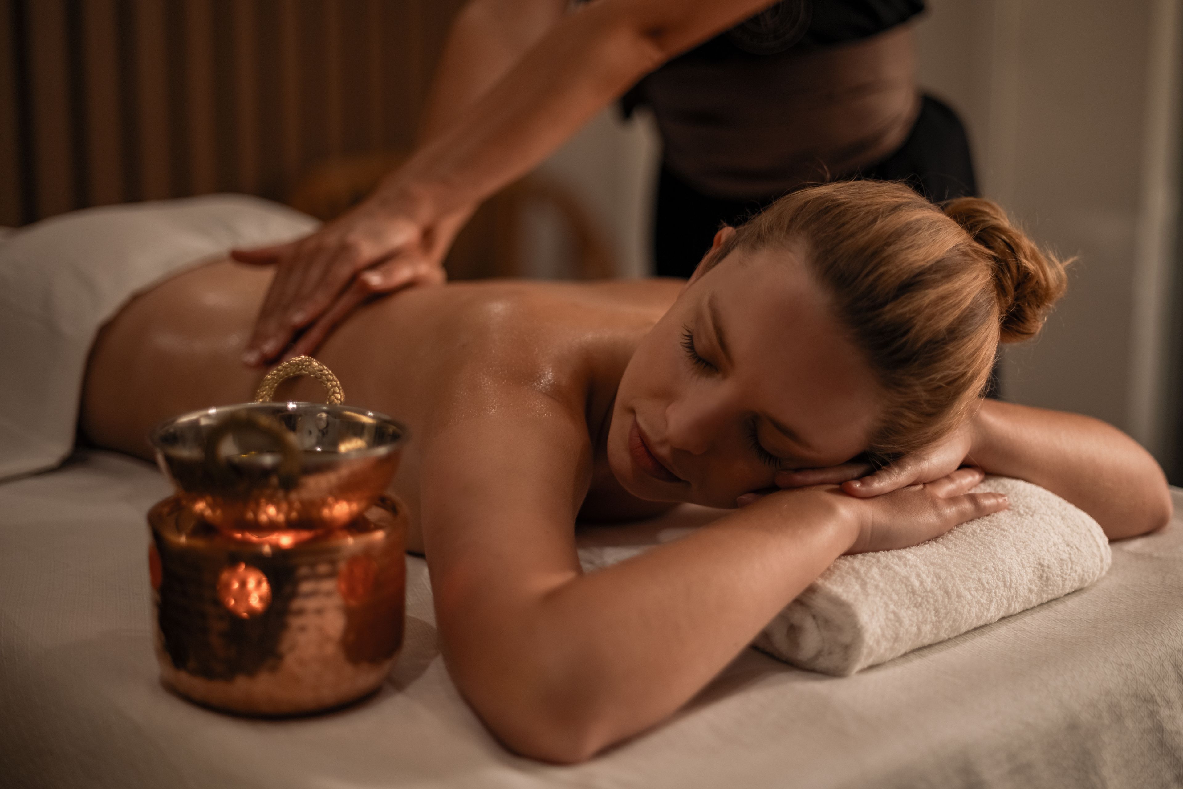 Eine Person bekommt eine Massage mit einem Kupfermassagegerät auf einer Massageliege.
