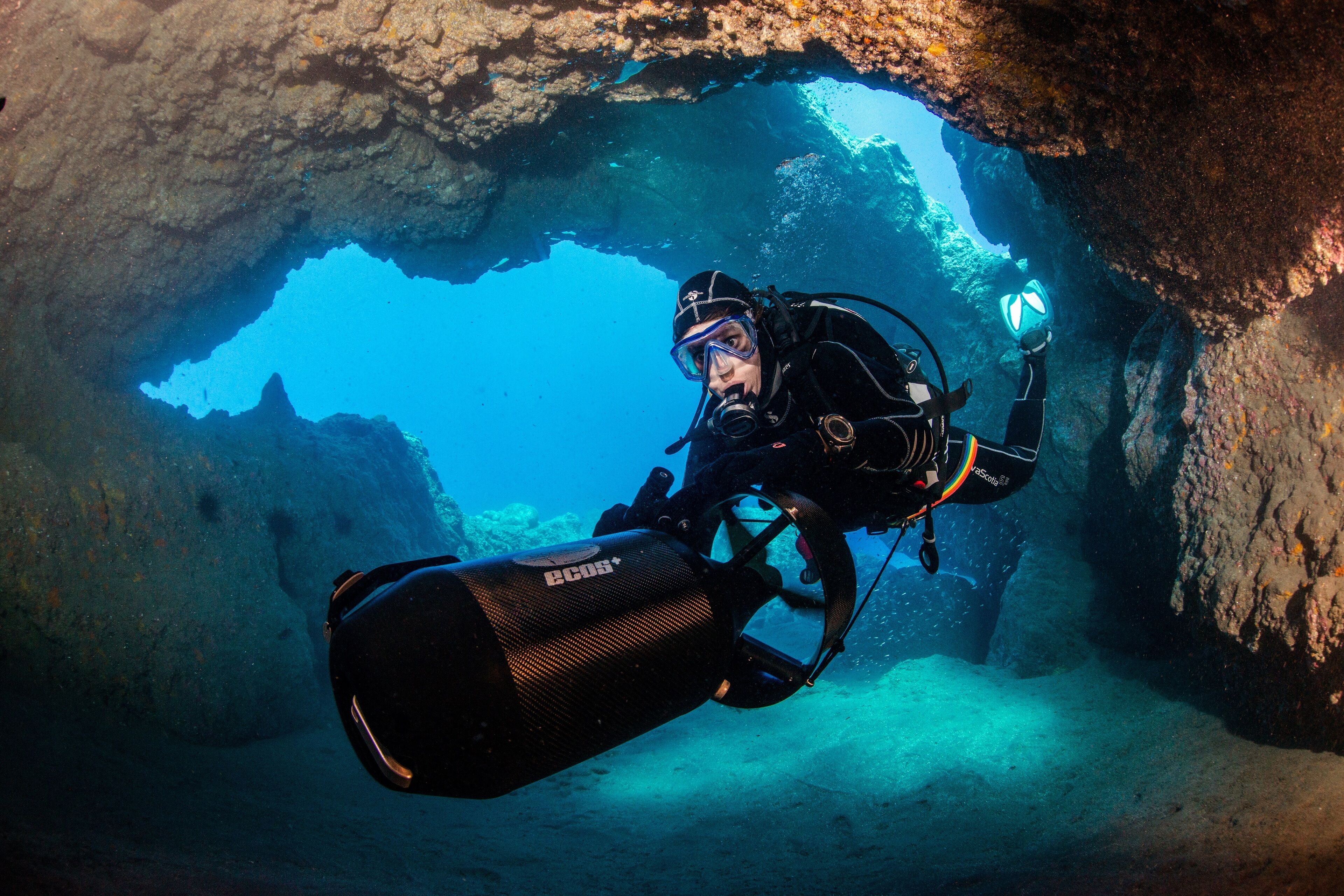 A diver in a cave with a large underwater camera.