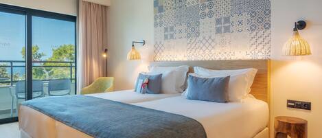 A modern hotel room with a large bed, a balcony with chairs, and a patterned wall.