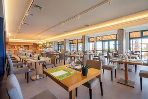 Un restaurante espacioso con varias mesas, sillas y una zona de bar.