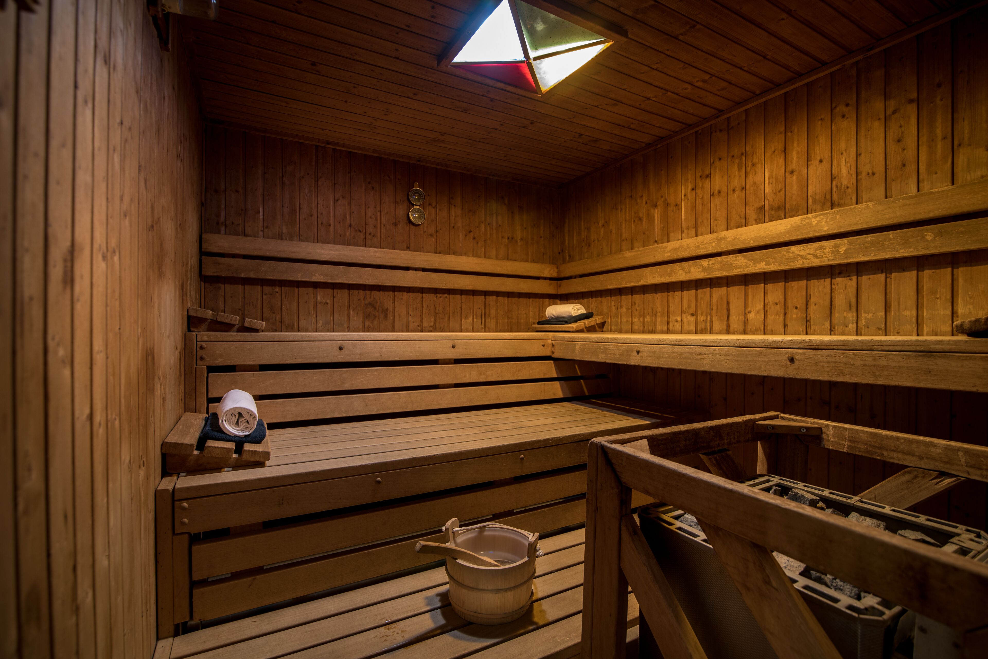 Uma sauna com bancos de madeira, um balde e um relógio.