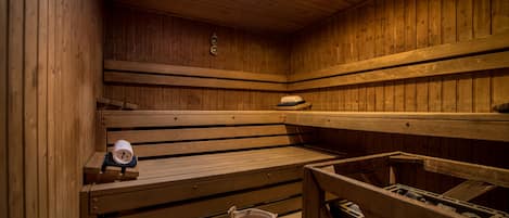 Eine Sauna mit Holzbänken, einem Eimer und einer Uhr.