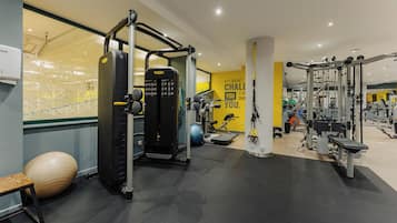 Un gimnasio con diversos equipos de ejercicio, una pelota de gimnasia grande y una frase motivacional en la pared.