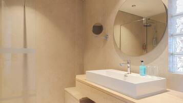 A modern bathroom with a large rectangular sink, a round mirror, and a glass-enclosed shower.