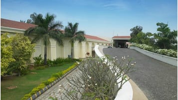 Um edifício com telhado de telhas vermelhas, entrada coberta e calçada pavimentada.