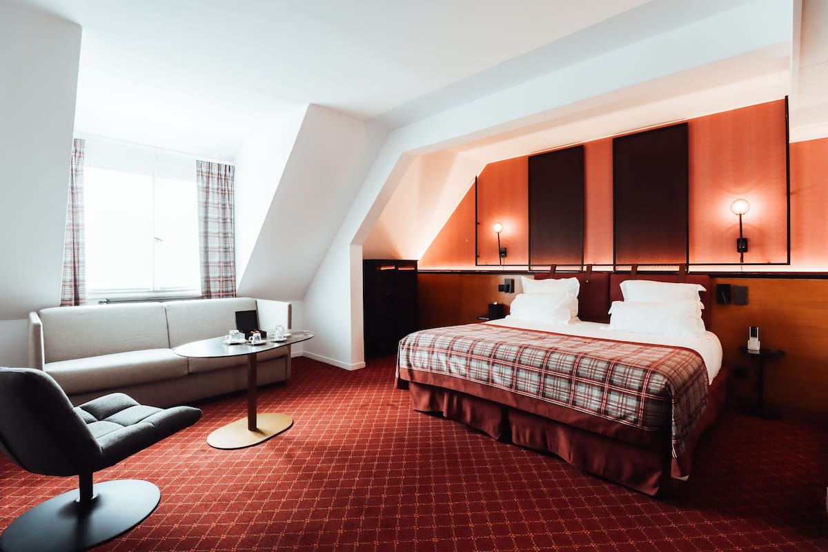 Ein Hotelzimmer mit einem Bett, einem Sofa, einem kleinen Tisch und einem Sessel.