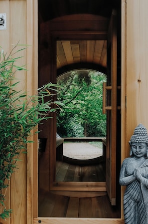 A wooden door leading to a circular viewing area with a statue on the right.