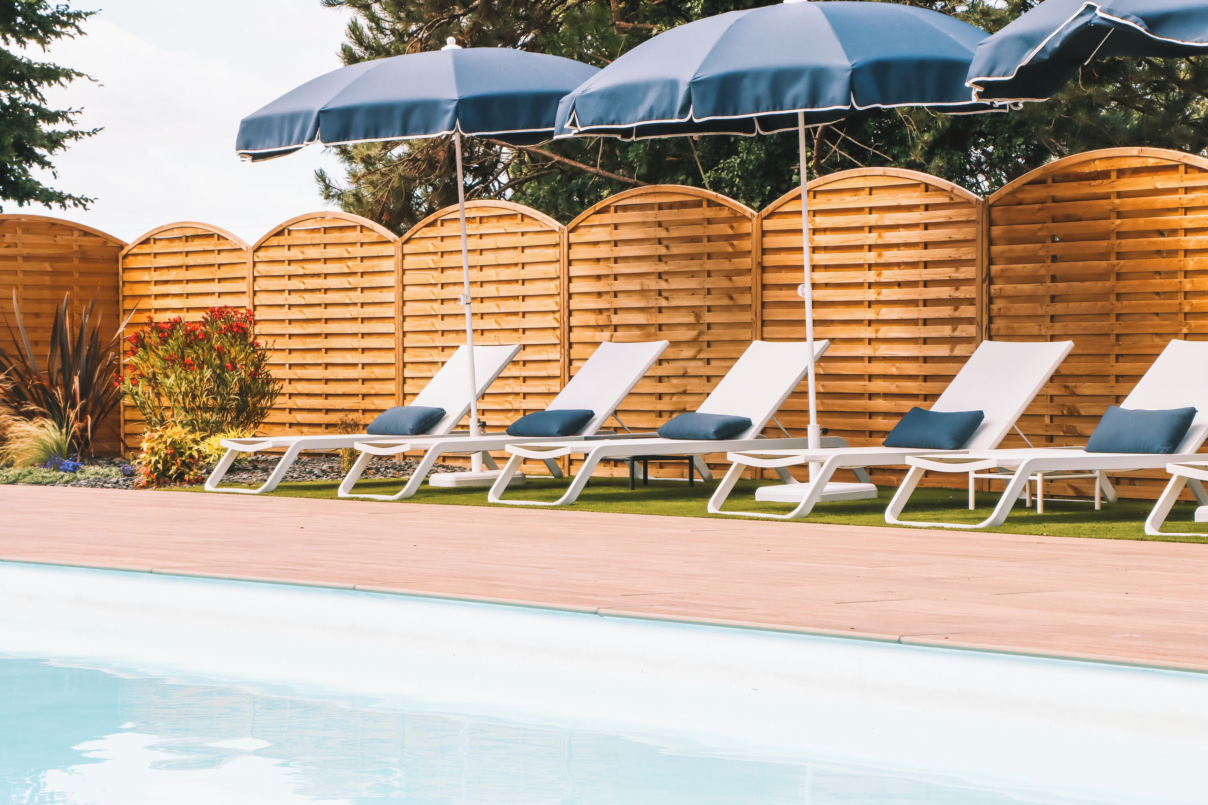 Un espace aménagé au bord de la piscine, avec des chaises longues et des parasols.