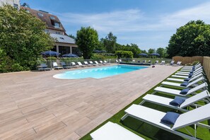 Una piscina al aire libre de temporada, sombrillas