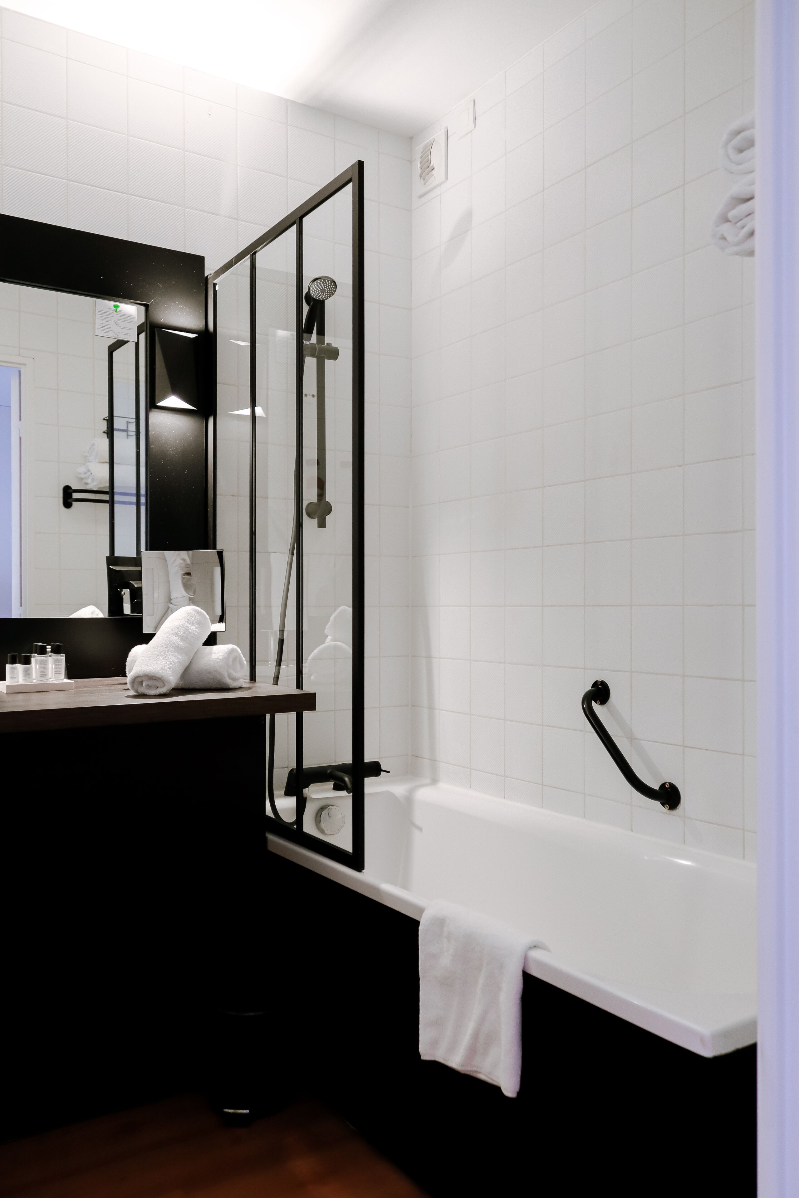 Un baño moderno con una bañera blanca, cabina de ducha con mampara de vidrio y mueble de tocador de madera oscura.