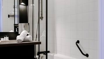 Un baño moderno con una bañera blanca, cabina de ducha con mampara de vidrio y mueble de tocador de madera oscura.