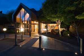A modern building with large glass windows, a well-lit entrance, and a landscaped garden area. - Dunedin Leisure Lodge - A Distinction Hotel (Dunedin)