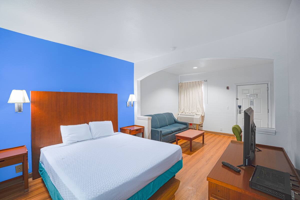 Une chambre d’hôtel avec un grand lit, un bureau avec un ordinateur, une chaise et un téléviseur.