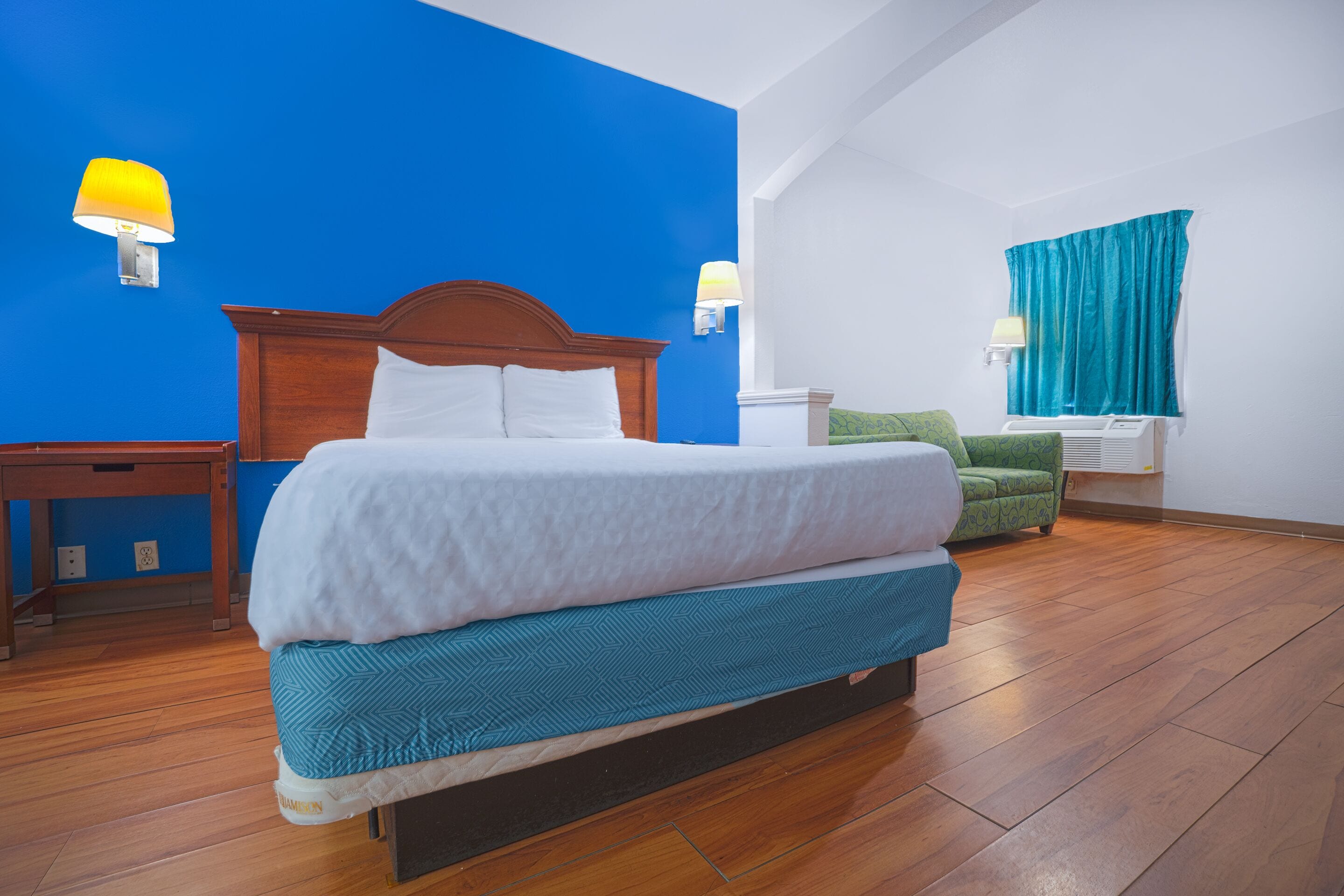 Een hotelkamer met een groot bed, een groene bank en een houten vloer.