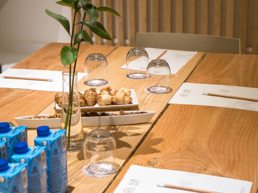 Una mesa de madera con una planta, vasos y alimentos.