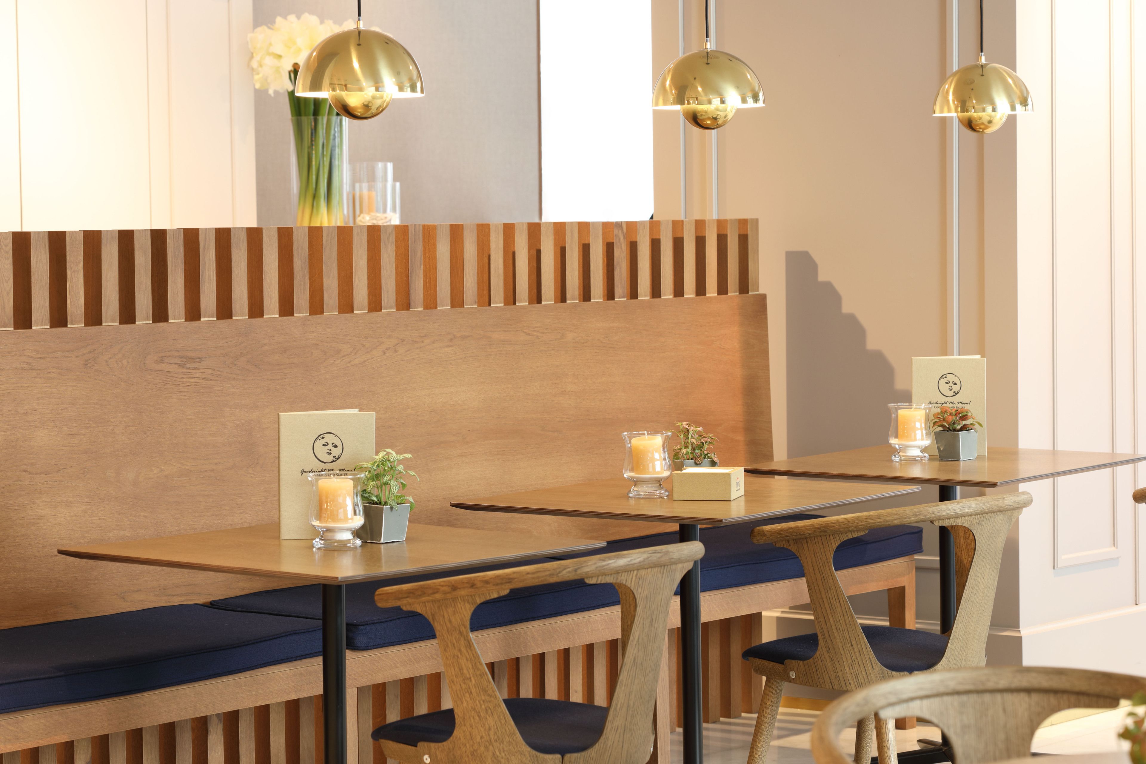 Un restaurante con bancos de madera, cojines azules e iluminación colgante.