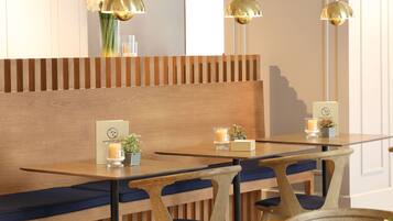 Un restaurante con bancos de madera, cojines azules e iluminación colgante.