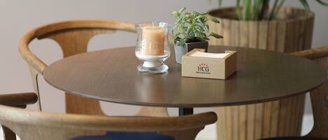 A round wooden table with a candle, a small potted plant, and a box labeled "HCG Hotel Cortez de Guatemala."