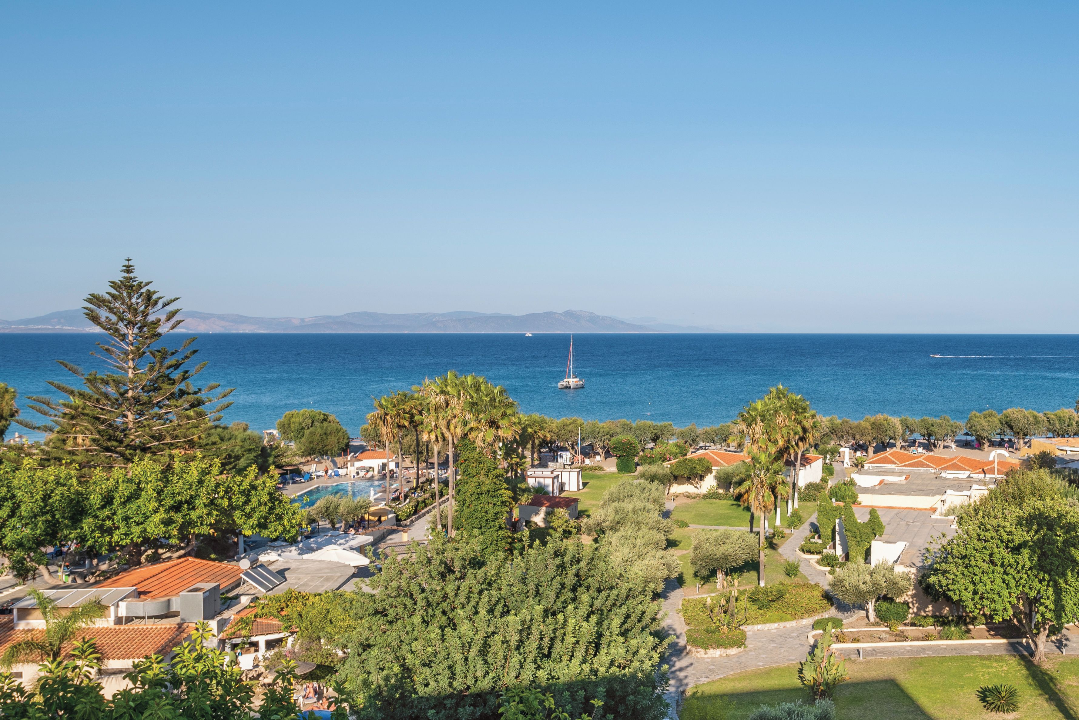A coastal residential area with houses, a swimming pool, and a view of the sea.