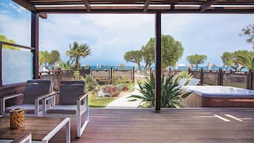 An outdoor deck with wooden furniture, a hot tub, and a view of the sea.