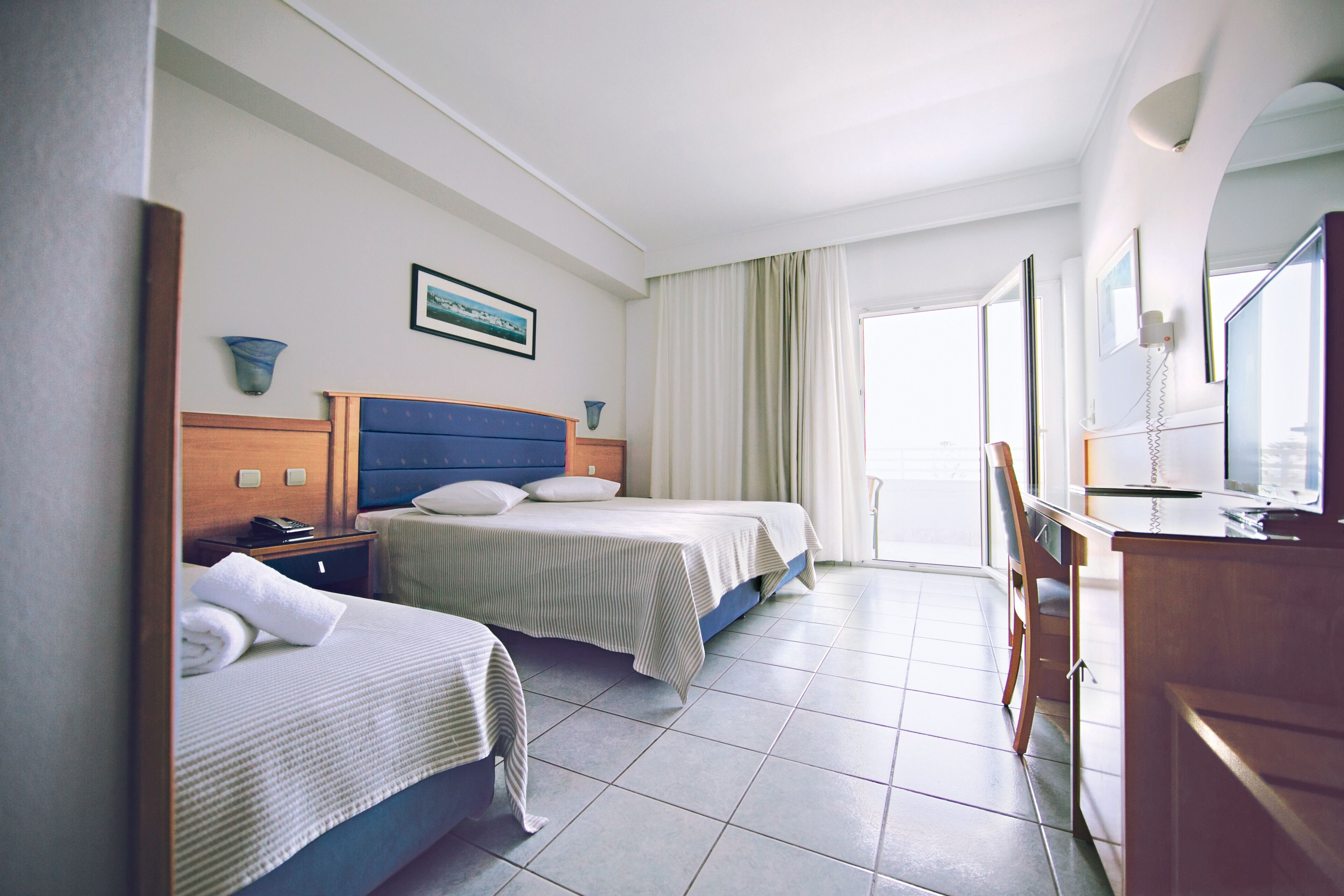 A hotel room with two beds, a desk, and a bathroom.