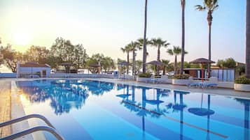 A swimming pool with lounge chairs and palm trees.