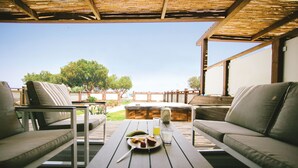 Un espacio al aire libre con mesa de madera, dos sofás y un jacuzzi.