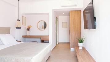 A modern hotel room with a bed, bedside table, mirror, and a flat-screen TV mounted on the wall.