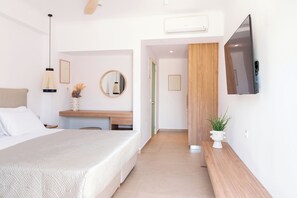 Een moderne hotelkamer met een bed, nachtkastje, spiegel en een wandgemonteerde flatscreen televisie.